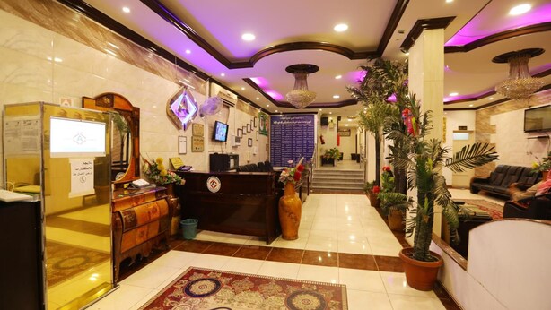 Un hall d’hôtel comprenant un comptoir d’accueil, un grand lustre et un espace de réception équipé d’un écran d’ordinateur.