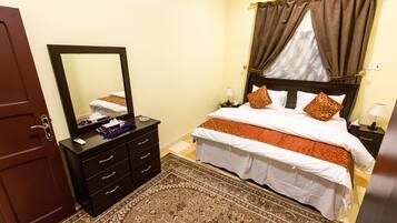 A hotel room with a bed, a dresser, a mirror, a nightstand, and a rug.