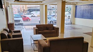 Un hall d’entrée avec un espace salon, une cloison en verre et une vue sur la rue.