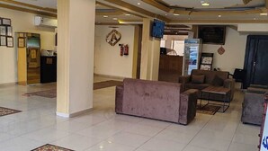 Un hall d’entrée spacieux, agrémenté d’un grand tapis décoratif, de sièges confortables et d’un design moderne au niveau du plafond.