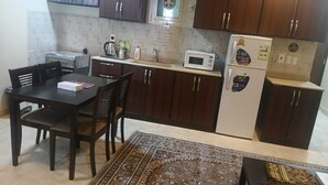 Une cuisine de taille réduite, dotée de meubles en bois foncé, d’un four à micro-ondes, d’un réfrigérateur et d’une table à manger avec des chaises.