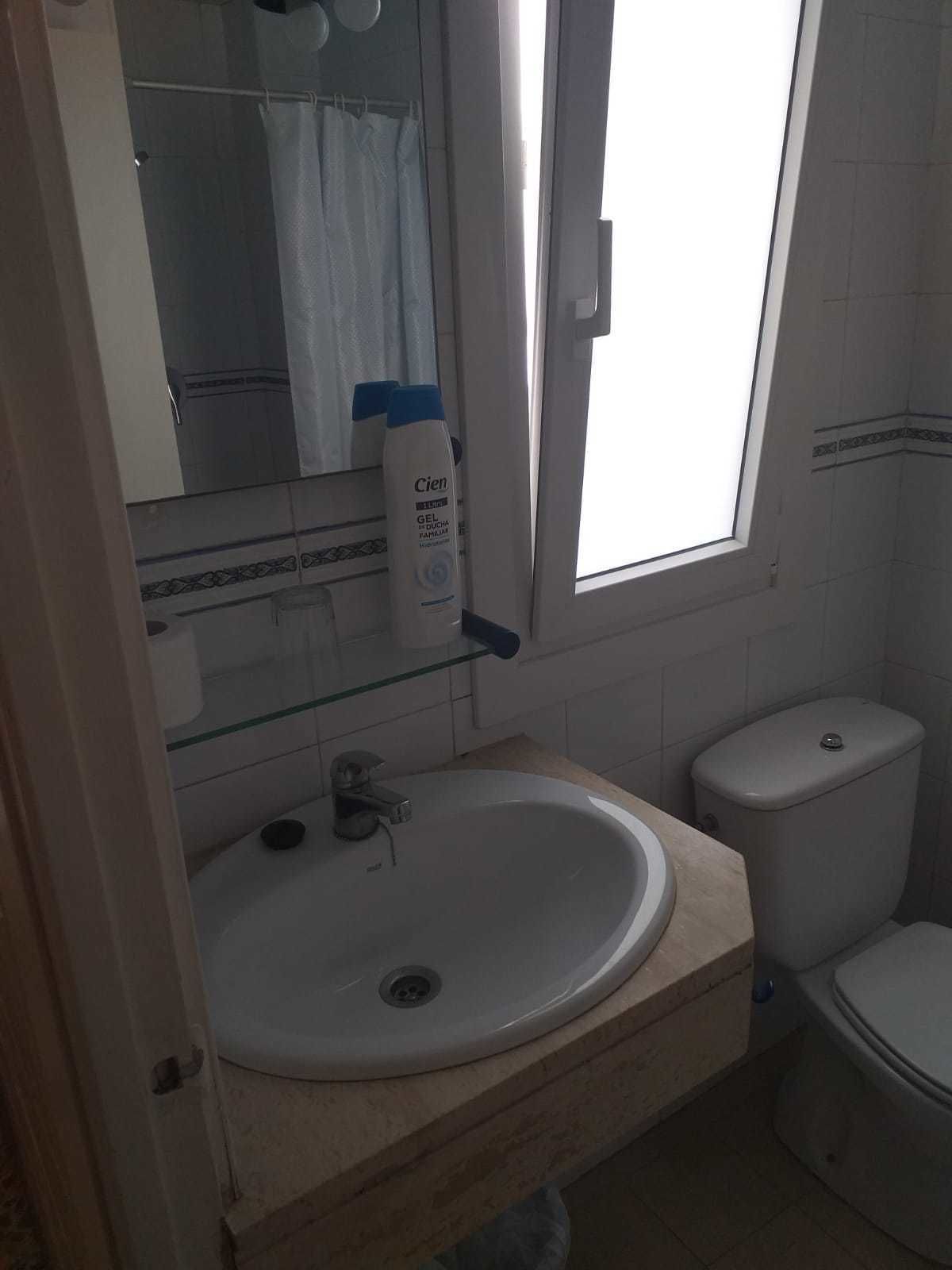 Ein Badezimmer mit einem weißen Waschbecken, einer Toilette und einem Glastablett mit Pflegeprodukten.