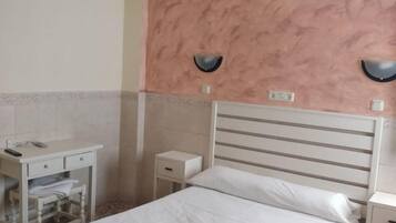 Un dormitorio con cama, mesitas de noche, espejo e iluminación en el techo.