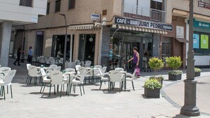 Un edificio con varios balcones y un café-bar llamado "Café-Bar Juan Pedro Pension" en la planta baja.