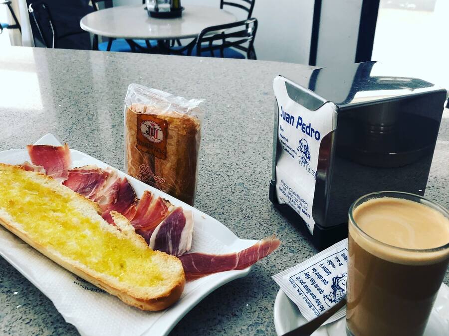 A meal with bread, ham, and a drink on a table in a cafe.