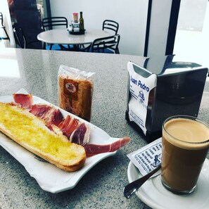 A meal with bread, ham, and a drink on a table in a cafe.