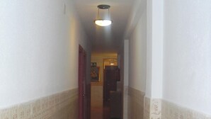 Un pasillo estrecho con paredes estampadas y suelo moteado, que conduce a una puerta al final.