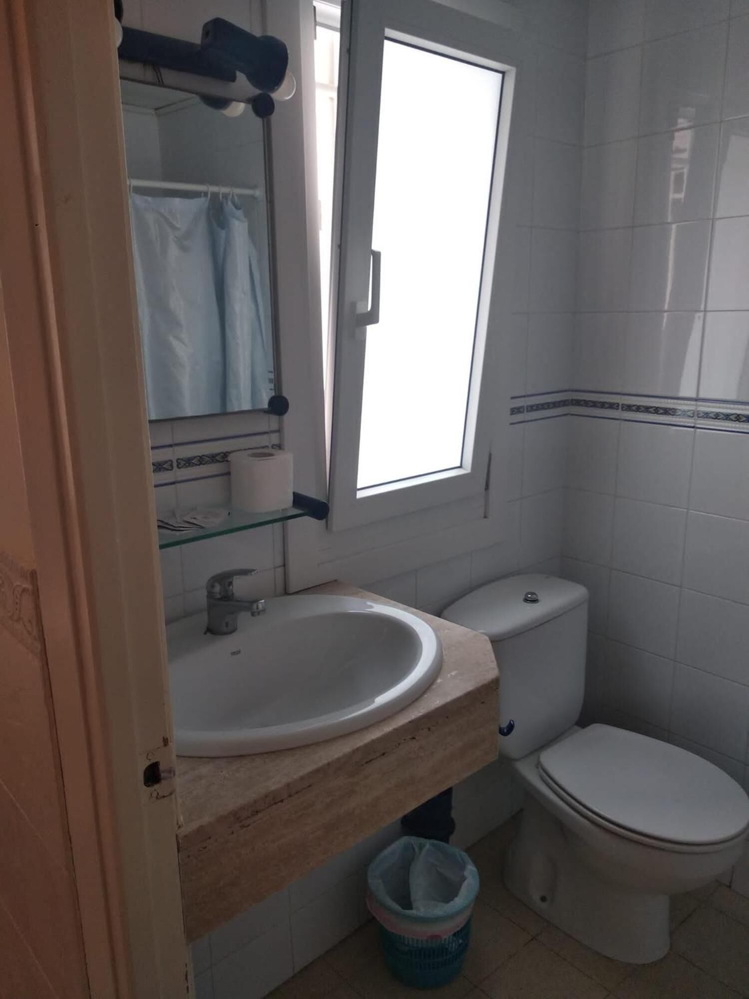 Un baño con lavamanos, inodoro y ventana.
