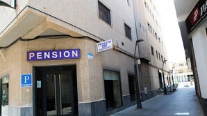 Un edificio con un letrero que dice 'PENSION JUAN PEDRO', un letrero de estacionamiento y una entrada visible.