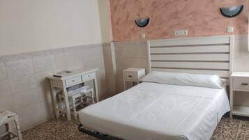 A hotel room with a bed, a desk, a chair, and a nightstand.