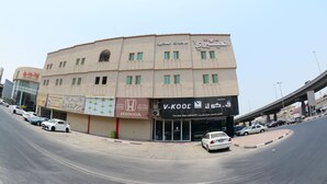 Un edificio de varios pisos con diversos comercios en la planta baja, incluyendo un centro de repuestos Honda y una tienda V-Kool.
