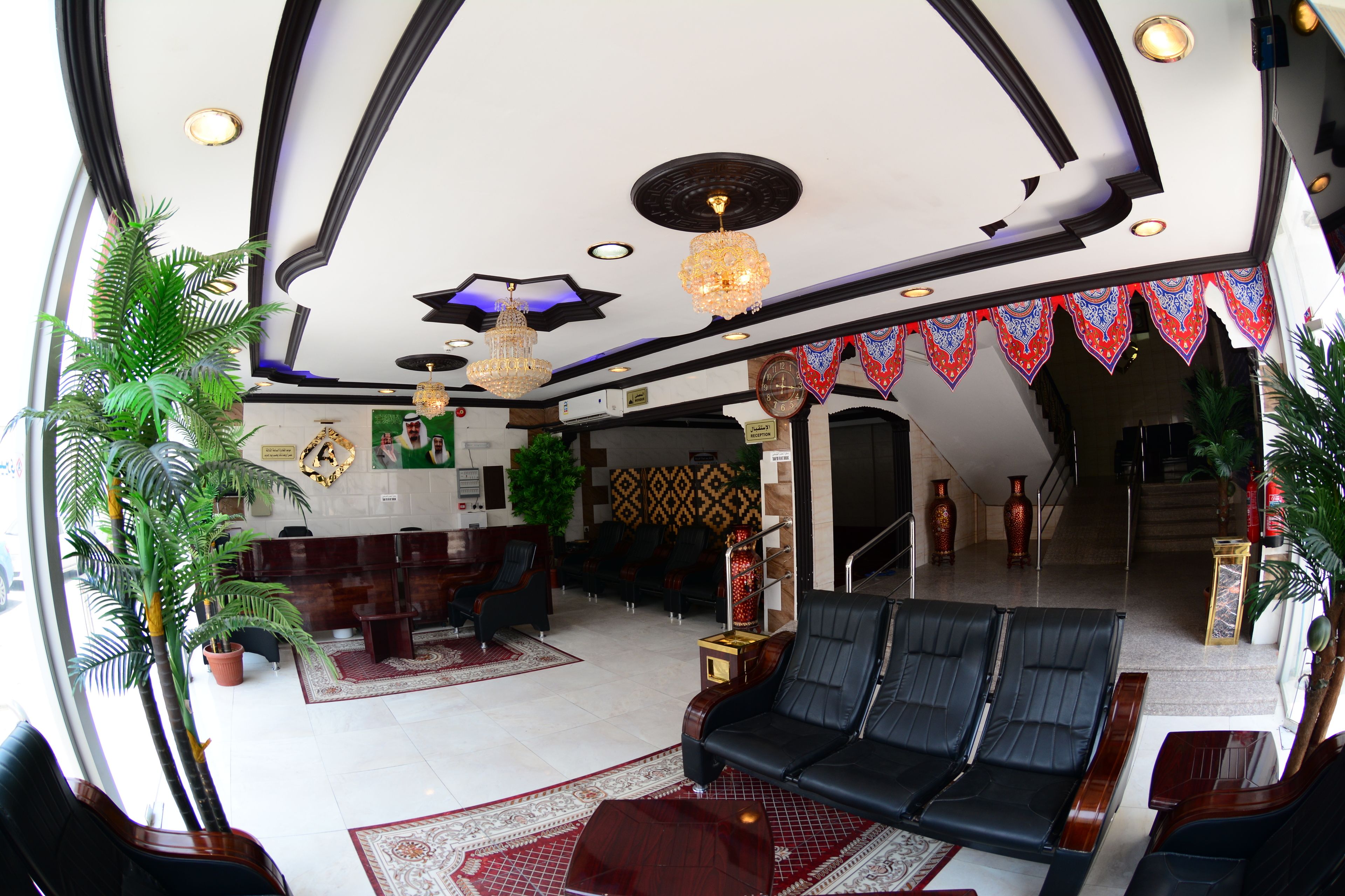 A spacious lobby with a black leather sofa, a reception desk, and a patterned ceiling.
