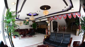 A spacious lobby with a black leather sofa, a reception desk, and a patterned ceiling.