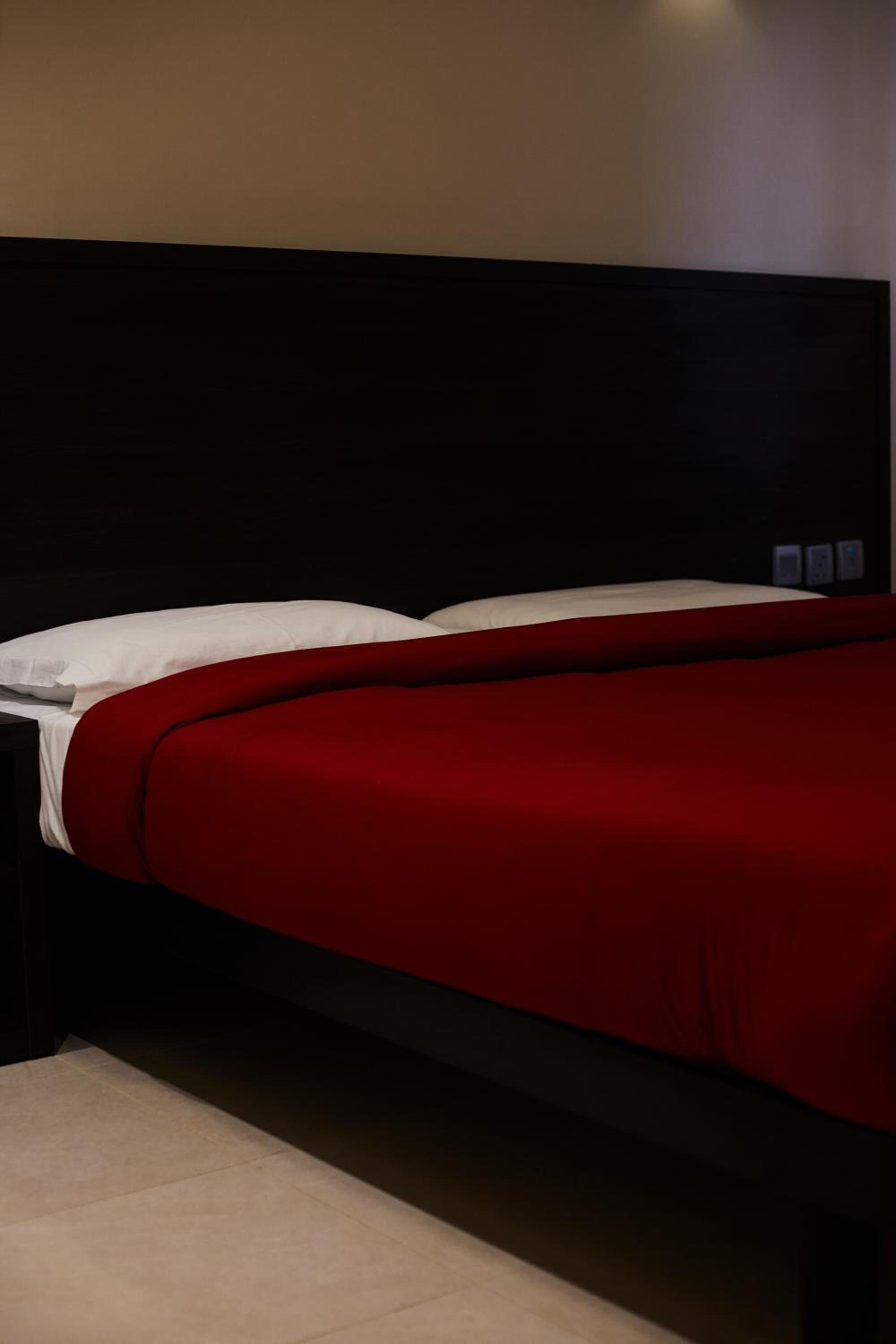 A bed with a dark headboard and red bedding.