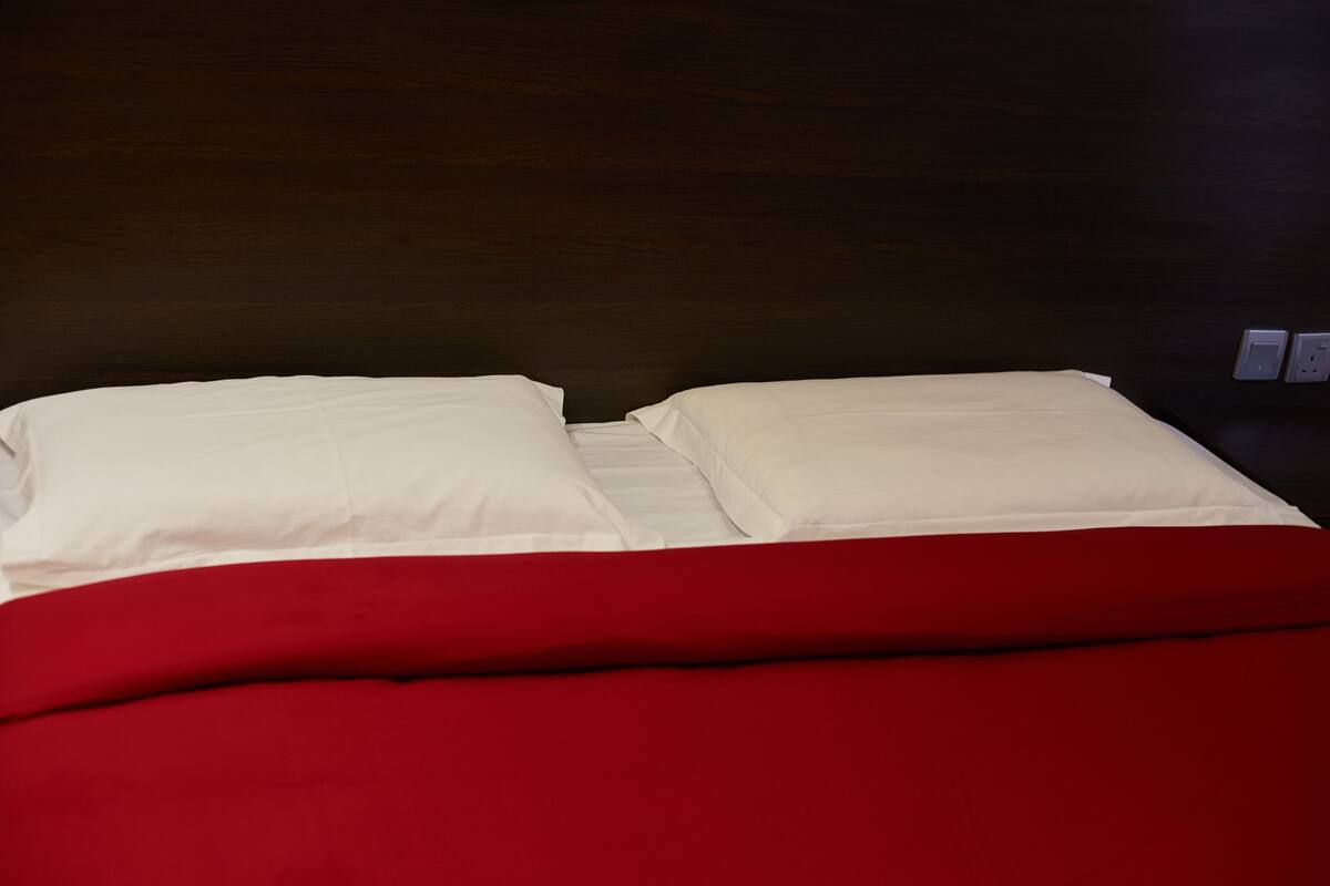 A bed with white bedding and a red blanket.