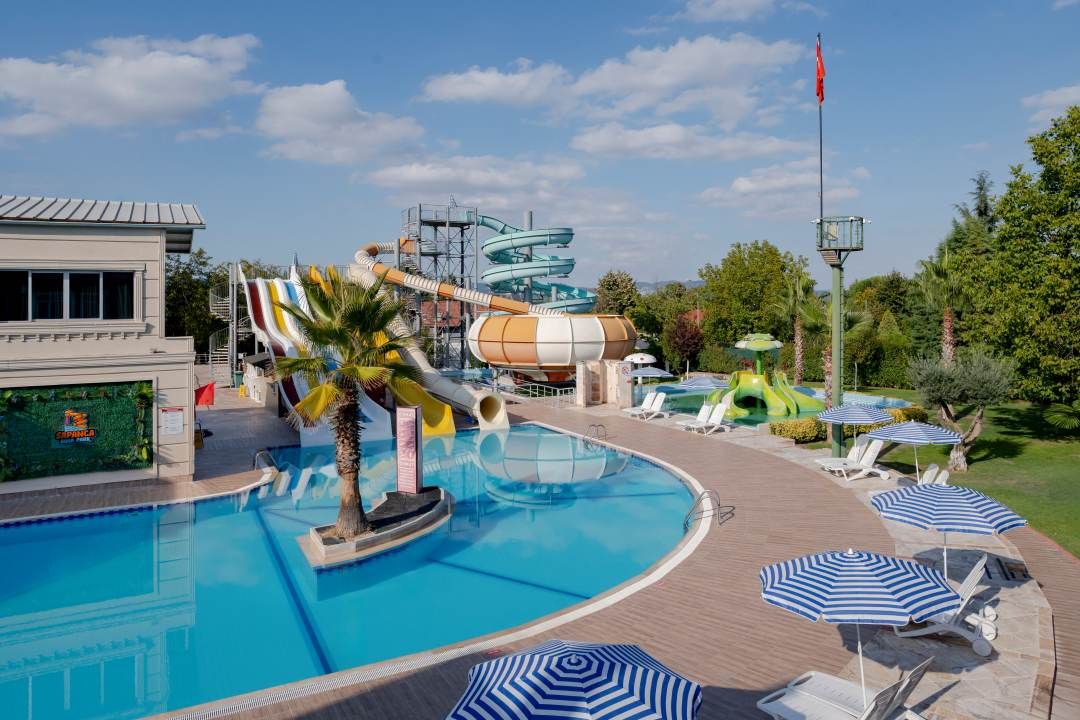 Una piscina con tobogán, sillones de playa y sombrillas.