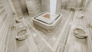 Ein luxuriöses Badezimmer mit zentraler Fußbodenheizung, Marmorwänden und mehreren Waschbecken.