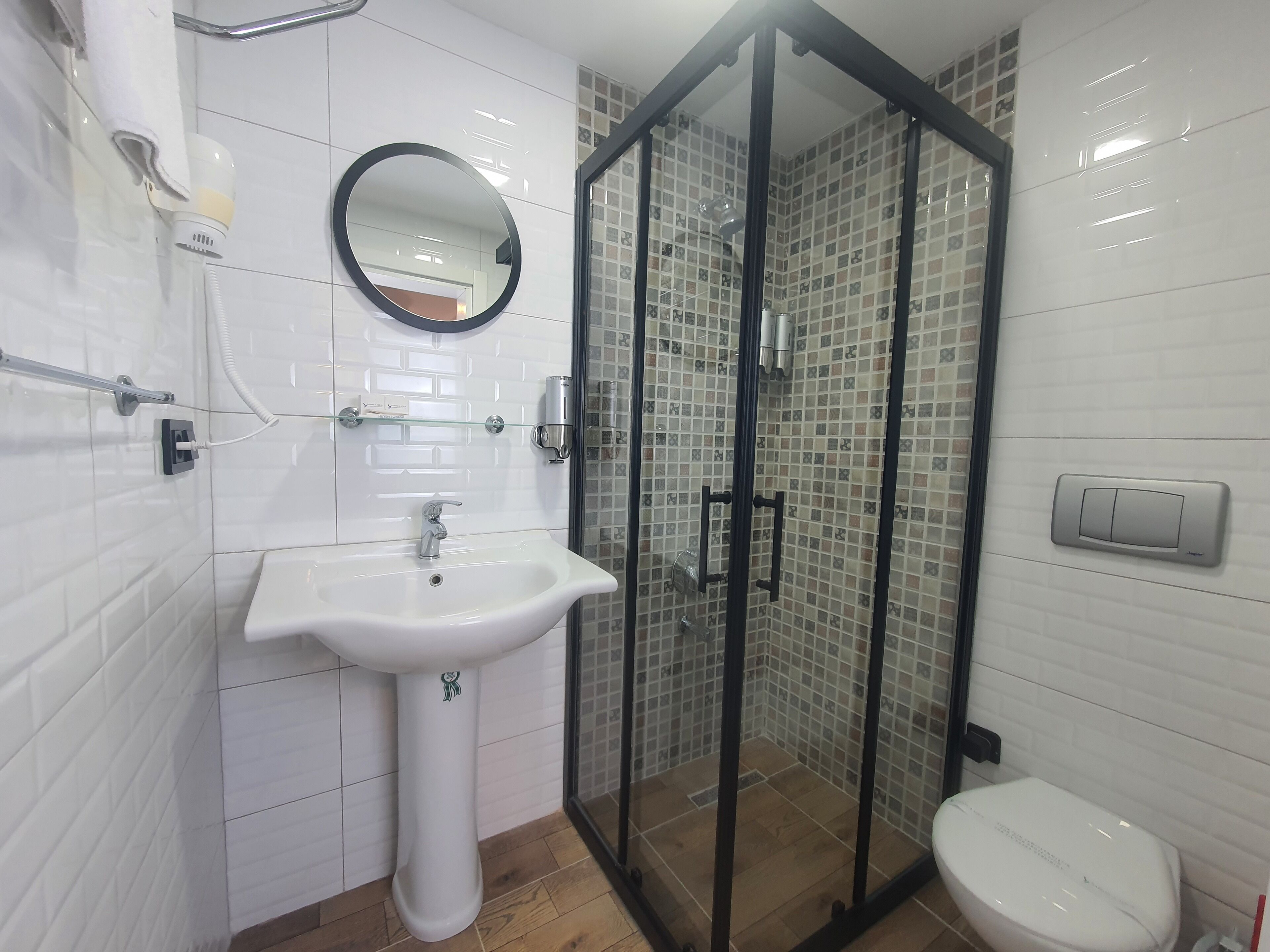 A modern bathroom with a white sink, a glass shower enclosure, and a toilet.