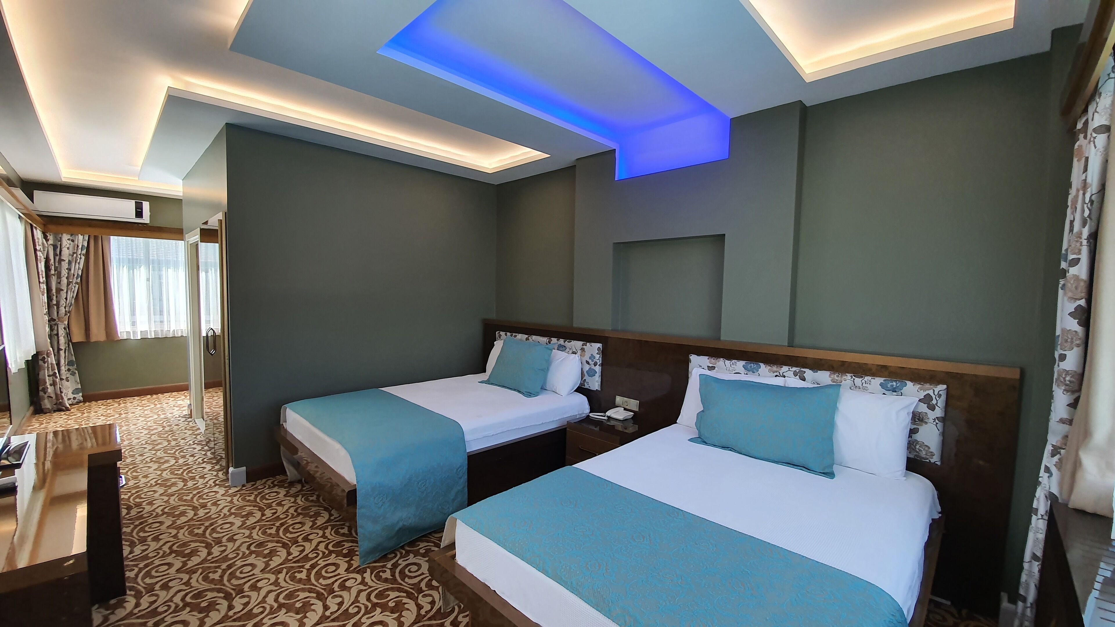 Een hotelkamer met twee bedden, een bureau en een kamerbreed tapijt met dessin.