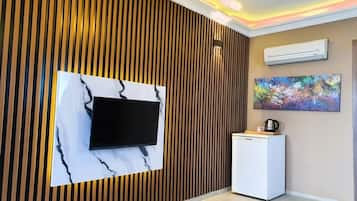 A modern room with a wooden slat wall, a flat-screen TV mounted on a marble-like surface, a small white cabinet, and an air conditioning unit on the wall.