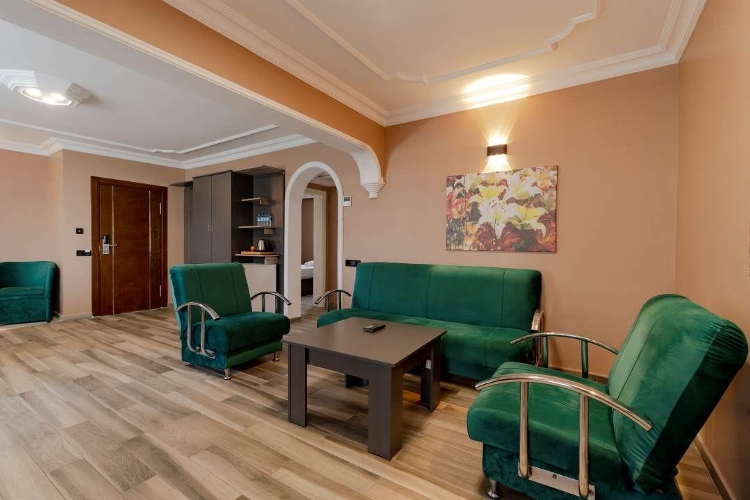A room with a green sofa set, a wooden coffee table, and a painting on the wall.