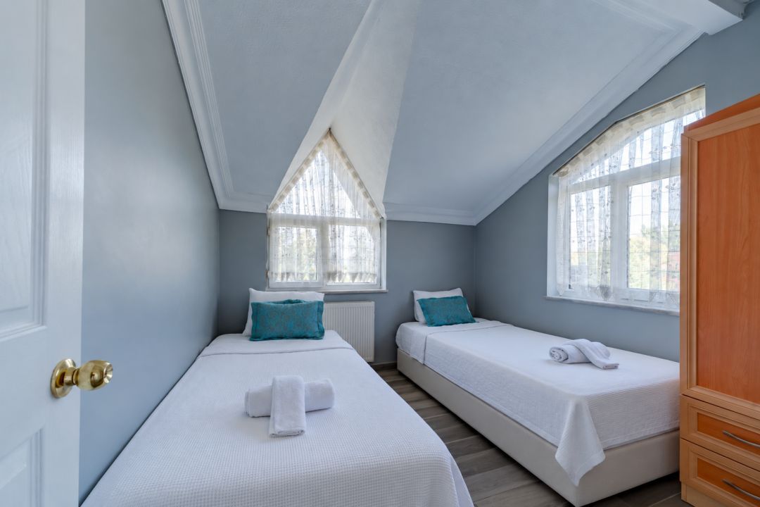 Une chambre avec deux lits simples, une armoire en bois et une fenêtre donnant sur un beau paysage.
