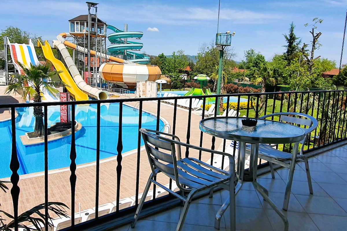 A pool area with a water slide, lounge chairs, and a table.