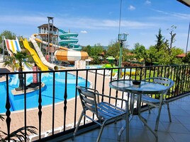 Un espace piscine équipé d’un toboggan, de chaises longues et d’une table.