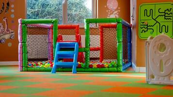 A play area with a netted enclosure, colorful balls, and a blue step.
