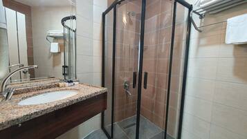 A modern bathroom with a glass-enclosed shower, a granite countertop sink, and a mirror.
