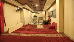 Un couloir d’hôtel avec un tapis rouge, une rambarde en verre et un rideau rouge.