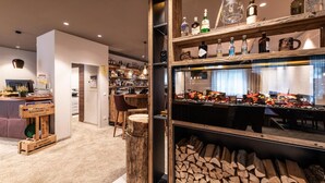 Een bar met drankflessen op planken, een houten toog en een zithoek met stoelen en een tafel.
