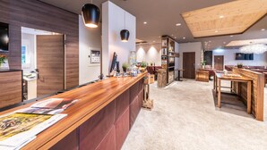 Een moderne receptiebalie met een houten toonbank, een grote spiegel en een plafond met zichtbare balken.