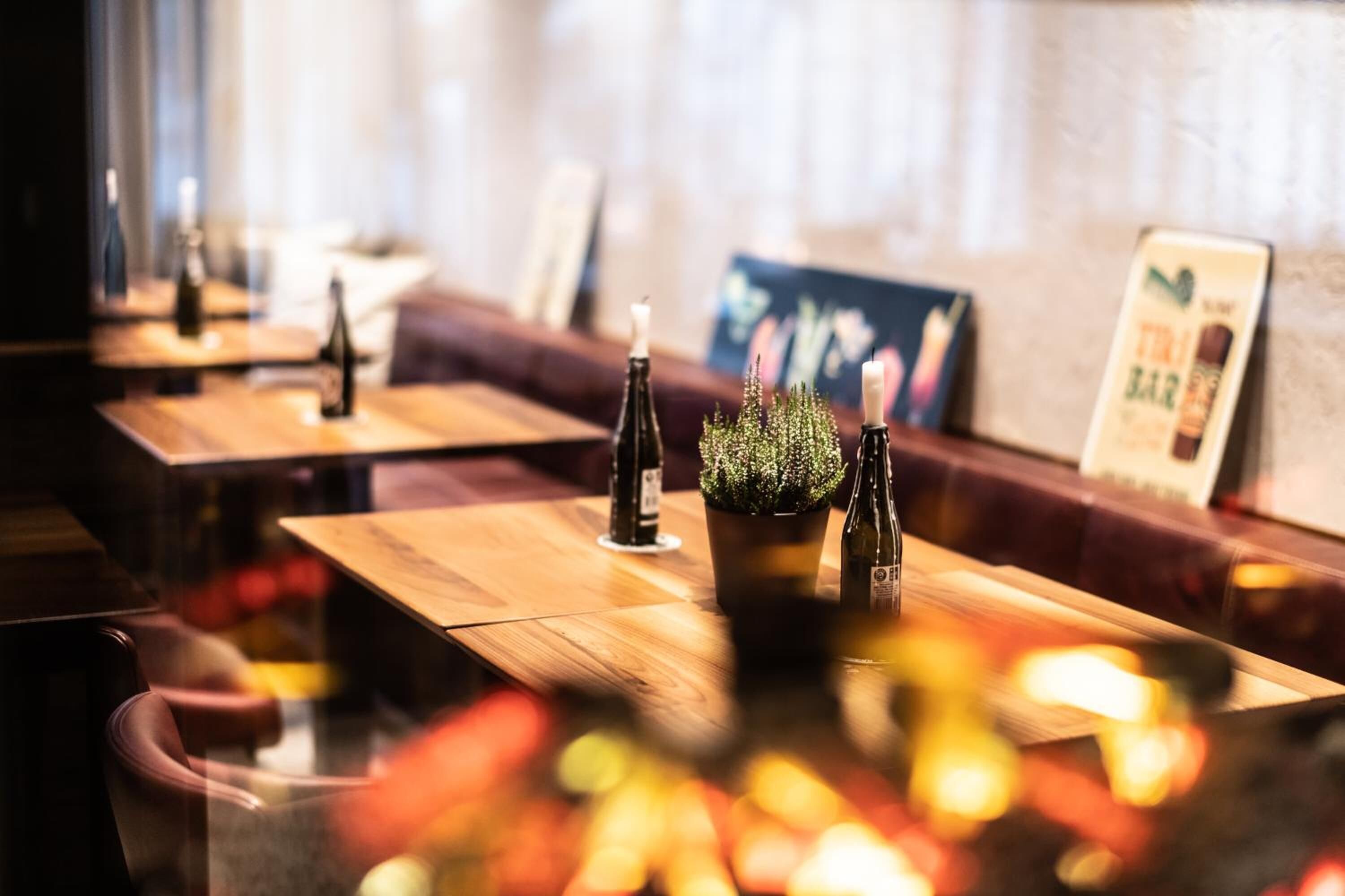 A restaurant with wooden tables, potted plants, and a bar area.