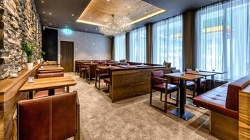 Un restaurante moderno con mesas de madera y asientos de cuero, paredes de piedra y ventanas amplias.
