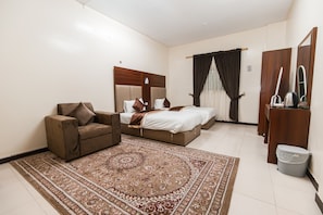 A hotel room with a bed, a sofa, a carpet, a wardrobe, and a mirror.