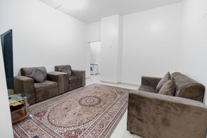 A living room with two sofas, a glass coffee table, and a patterned rug.