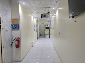 Un couloir avec un extincteur, un panneau indiquant le numéro 930 et un projecteur fixé au plafond.