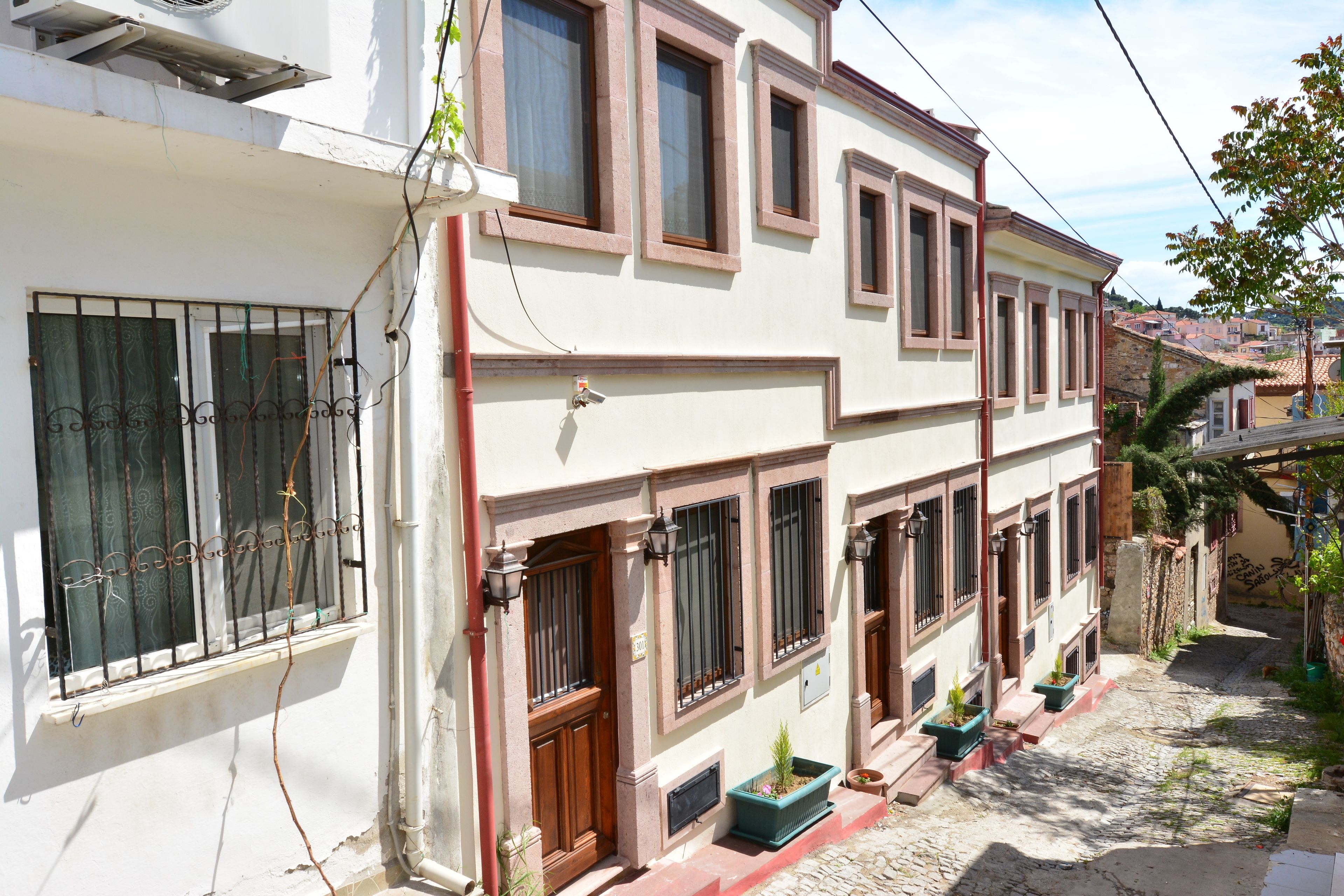 A two-story building with a white facade, multiple windows with brown frames, and a cobblestone street.