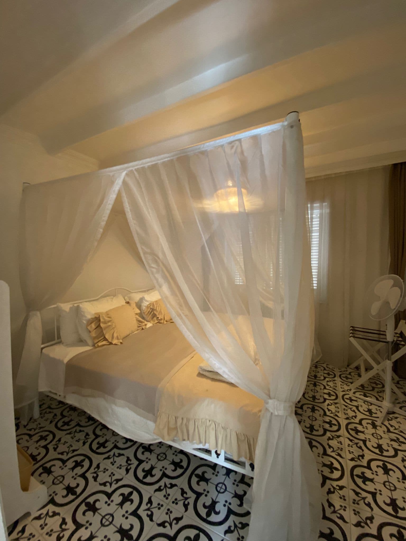 Una cama con dosel, una mesita de noche y una silla.