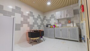 Une cuisine avec des murs recouverts de carreaux blancs, un plafond en bois et un four à micro-ondes posé sur le plan de travail.