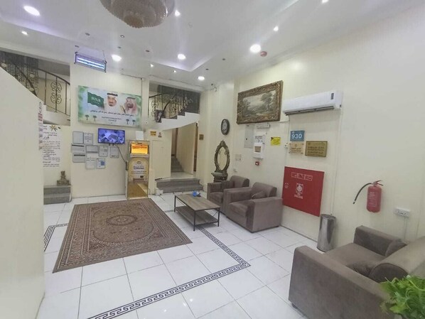 A lobby with a staircase, seating area, and a reception desk.