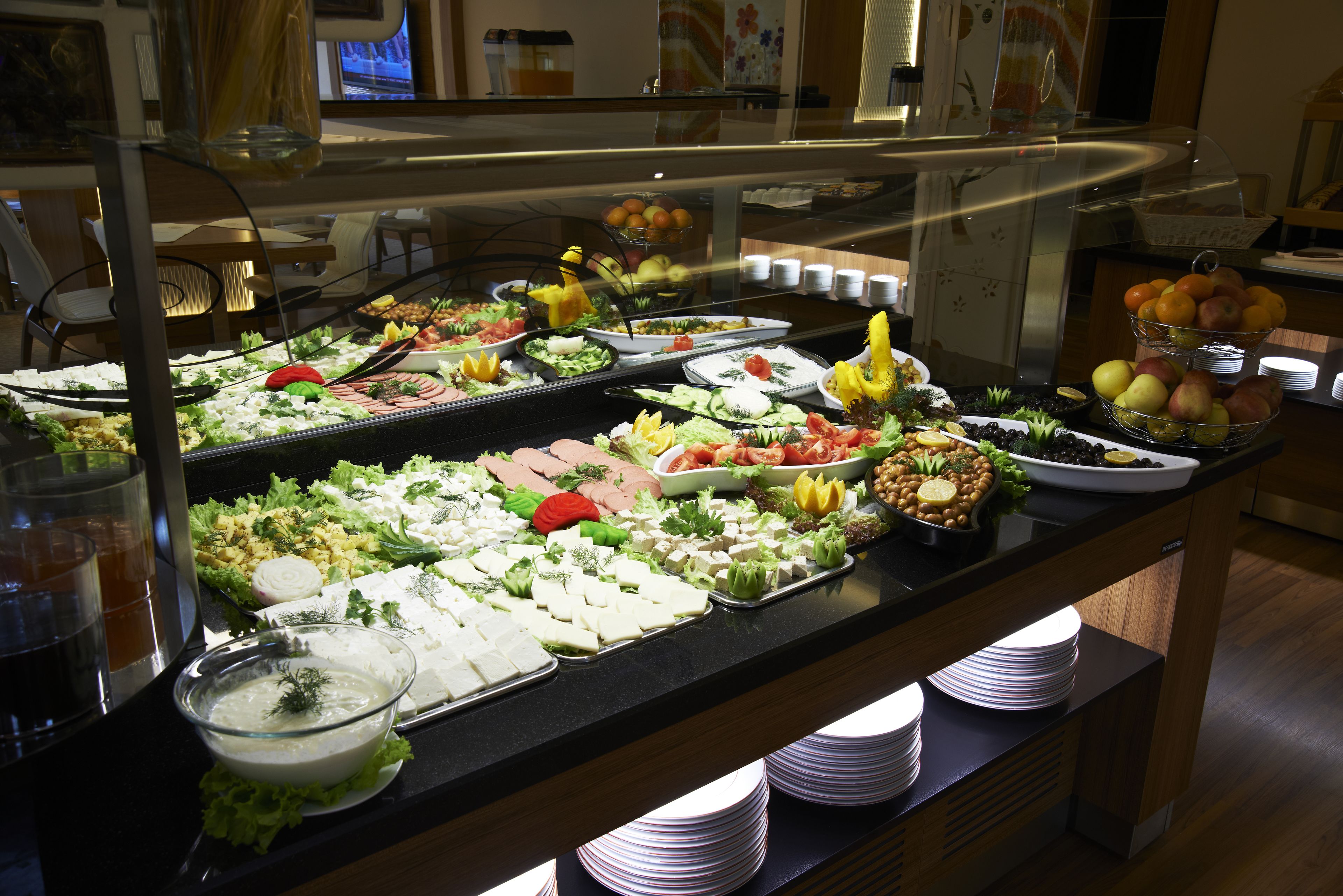 A buffet with various food items and a glass bowl of salad.