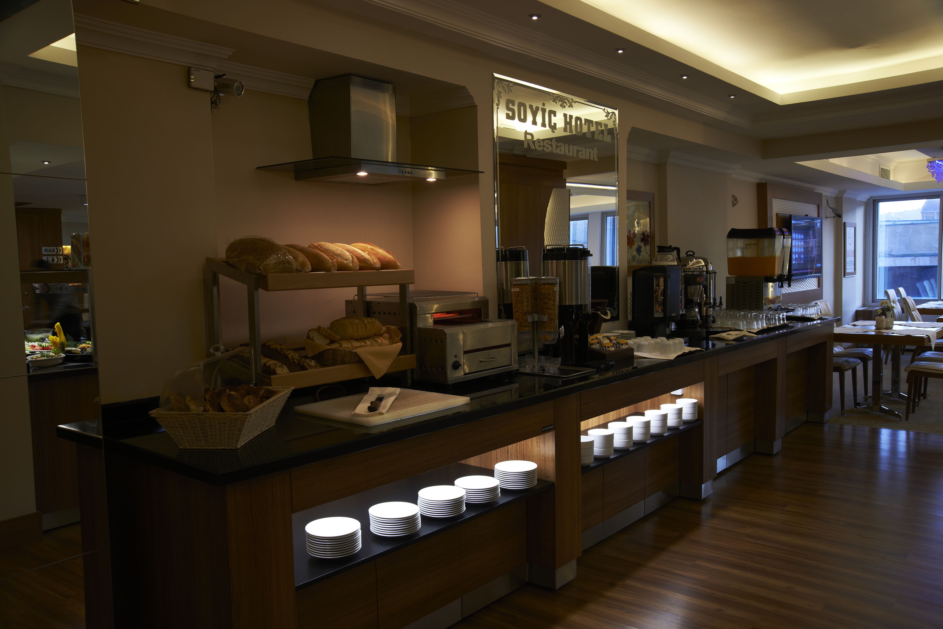 A breakfast bar with bread, coffee machines, and a sign reading "SOYIC HOTEL Restaurant".