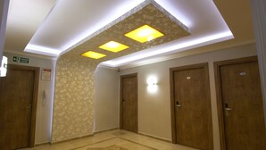 A hotel corridor with wooden doors, a patterned wall, and recessed ceiling lights. - Soyic Hotel (Eskisehir)