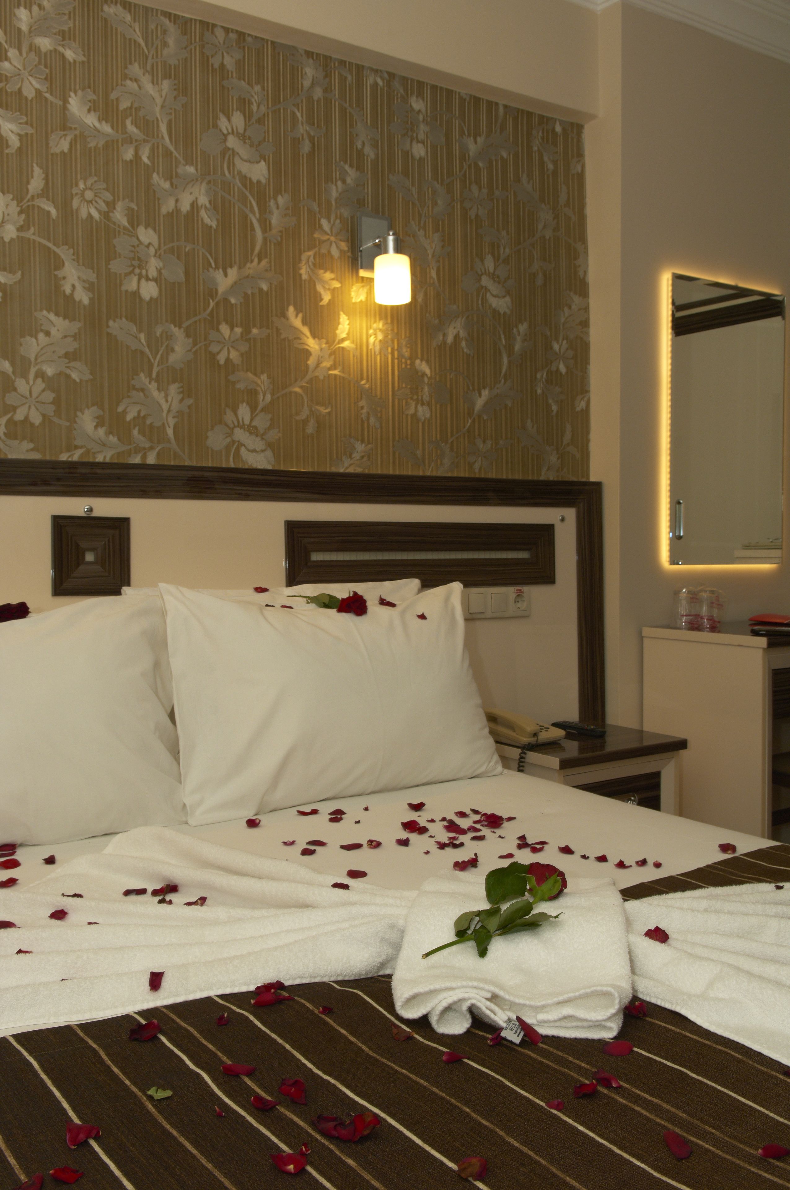 Una habitación de hotel con una cama bien hecha, una mesita de noche con lámpara y un espejo en la pared.