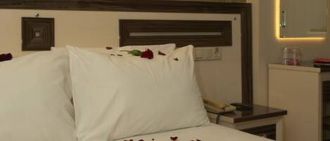 Una habitación de hotel con una cama bien hecha, una mesita de noche con lámpara y un espejo en la pared.