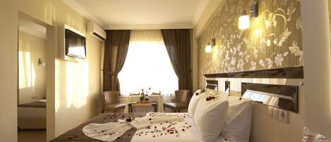A hotel room with a large bed, a desk, a chair, and a view of the outdoors.