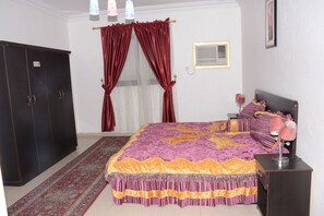 A bedroom with a bed, a wardrobe, a nightstand, and a window with curtains. - Al Eairy Furnished apt Al Madinah 1 (Madinah)