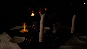 A dimly lit dining table with candles, glasses, and folded napkins, suggesting a romantic or intimate dining setting. - Explorer by eco team -Dambana (Mahiyanganaya)